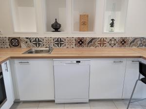 a kitchen with white cabinets and a sink at UN AIR DE VACANCES in Layrac
