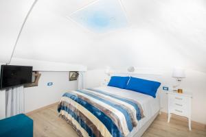 a bedroom with a bed with blue pillows and a tv at YourHome - Casa Barba Positano in Positano