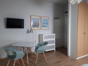 a living room with a table and chairs and a tv at Sosenka in Niechorze