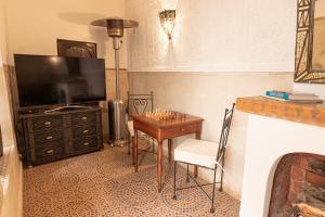 Una sala de estar con una mesa y un televisor. en Riad Ayada, en Marrakech