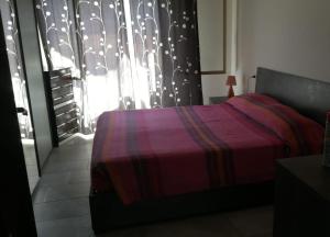 a bedroom with a bed and a window with a curtain at Appartamento Monte Argentu in Fluminimaggiore