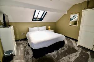 Un dormitorio con una gran cama blanca y una ventana en The Wrens en Leeds