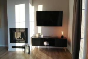 a living room with a television and a fireplace at Villa Corvus Mikołajki - Dom apartamentowy in Mikołajki