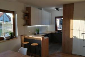a kitchen with white cabinets and a counter with stools at Villa Corvus Mikołajki - Dom apartamentowy in Mikołajki