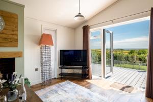 een woonkamer met een televisie en een glazen schuifdeur bij Edge of Padstow, 2 bedroom luxury lodge in Padstow
