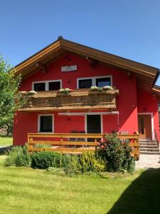 a red house with a balcony and a wooden fence at Landhaus Elto in Kaprun