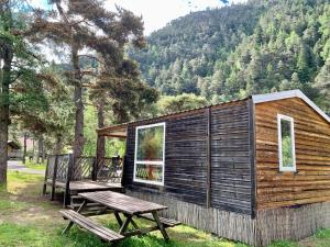 a wooden cabin with a picnic table and a bench at Camping River in Le Martinet