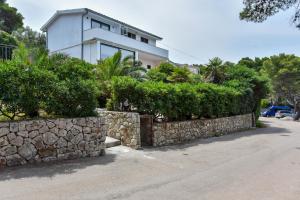 una casa con una pared de piedra y arbustos en Lazaneo Seafront Apartments, Jelsa Hvar en Jelsa