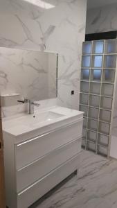 a white bathroom with a sink and a mirror at Holidays Domus Iano in Esparraguera