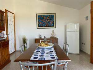 Oro Tramonto في توري دي كورساري: غرفة طعام مع طاولة وثلاجة بيضاء