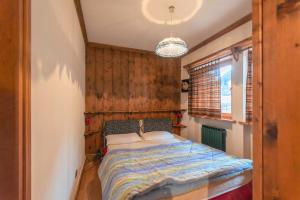 1 dormitorio con 1 cama con pared de madera en Ski Residence 3B en Falcade