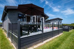 a house with an outdoor deck with an umbrella at Edge of Padstow, 2 bedroom luxury lodge in Padstow