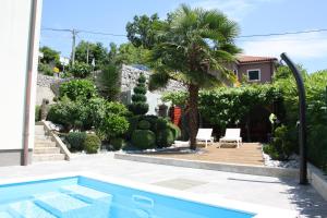 a pool in a yard with a palm tree and a house at Lux Villa in Rijeka