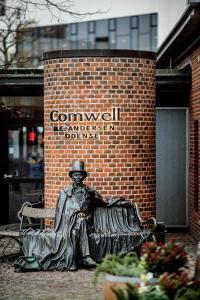 a statue of a man sitting in front of a brick building at Comwell H C Andersen Dolce by Wyndham in Odense