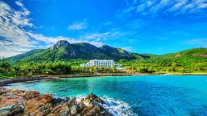 um resort numa praia com montanhas ao fundo em Orson Hotel & Resort Con Dao em Con Dao