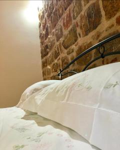 1 cama con sábanas blancas y pared de ladrillo en Appartamenti via cala sisine, en Santa Maria Navarrese