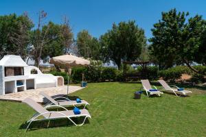 a group of lounge chairs and an umbrella on the grass at Eco Beachfront Villa in Gennadi