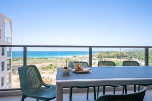 einen Tisch mit einer Schüssel Essen und Stühlen auf dem Balkon in der Unterkunft Beach Apartment in Achziv with Incredible Sea Views by Sea N' Rent in Naharija