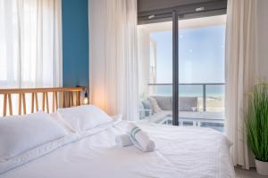 Schlafzimmer mit einem weißen Bett und Meerblick in der Unterkunft Beach Apartment in Achziv with Incredible Sea Views by Sea N' Rent in Naharija
