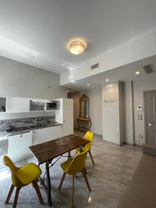 a kitchen with a wooden table and yellow chairs at Palazzo Novecento in Margherita di Savoia