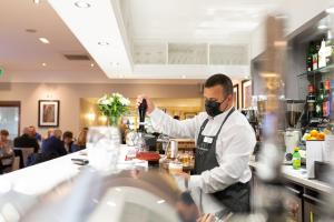 a man in a mask standing behind a counter at a bar at Rufford Arms Hotel in Rufford