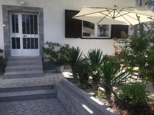 a white house with an umbrella and some plants at Apartment Paola in Opatija