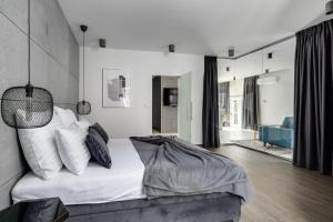 Schlafzimmer mit einem Bett mit weißer Bettwäsche und Kissen in der Unterkunft EL Apartments - Lupus in Posen