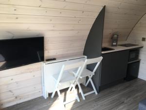 a kitchen with two chairs and a desk with a tv at Low Greenlands Holiday Park - Luxury House & Luxury Glamping Pods in Lancaster