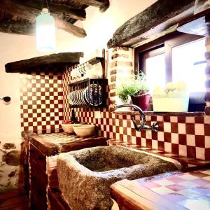 uma cozinha com um lavatório e uma parede xadrez em Casa del Cerro em Pedroche