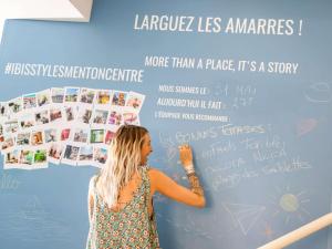 a woman standing in front of a wall with writing on it at Ibis Styles Menton Centre in Menton