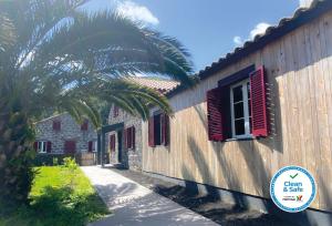 a building with red shuttered windows and a palm tree at Sete Cidades Nature Villa in Sete Cidades