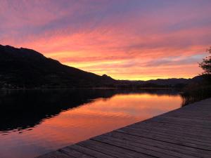 einen Sonnenuntergang über einem See mit einem Holzsteg in der Unterkunft Valsugana d'incanto in Tenna