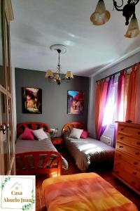 um quarto com 2 camas e uma cómoda e cortinas em Casa Abuelo Juan - Benaocaz- 2 dormitorios em Benaocaz