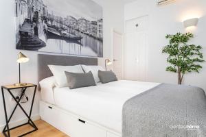 a white bedroom with a large white bed with two pillows at Genteel Home Castilla Terrace in Seville