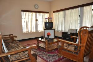 a living room with wooden chairs and a tv at Nandanam Homestay in Trivandrum