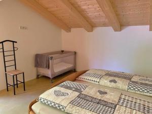 2 Betten in einem Zimmer mit einer Leiter und einem Stuhl in der Unterkunft Ferienwohnungen Kieferbachtal in Kiefersfelden