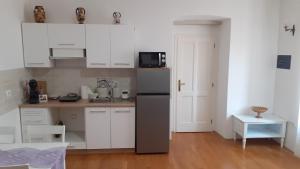 a small kitchen with white cabinets and a refrigerator at Apartments Villa Sandi in Izola