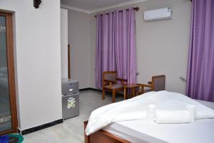 een slaapkamer met een bed en een tafel en stoelen bij Hancol Hotel in Dodoma