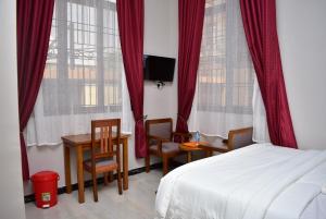 Hancol Hotel في دودوما: غرفة نوم بسرير وطاولة وكراسي