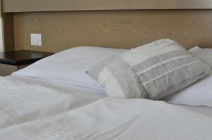 un letto bianco con un cuscino sopra di Hotel Scoiattolo a Baselga di Pinè