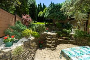 a garden with plants and a stone wall at Cecey Vendégház in Eger