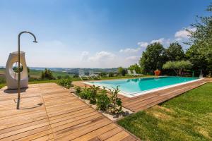 una piscina en un patio con terraza de madera en Villa Aurora, en Trecastelli