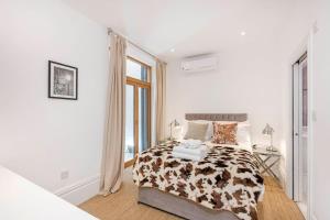 ein weißes Schlafzimmer mit einem Bett und einem Fenster in der Unterkunft 2 bed garden flat with air con by Fulham Broadway in London