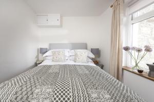 - une chambre blanche avec un grand lit et une fenêtre dans l'établissement Greenfields Coach House, à Marazion