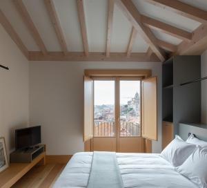 a bedroom with a bed and a large window at Na Travessa Suítes in Porto