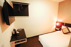 a hotel room with a bed and a flat screen tv at K Garden Hotel Parit Buntar in Parit Buntar