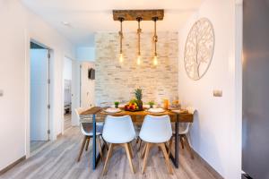a dining room with a wooden table and white chairs at Kanmarala in Alhaurín de la Torre