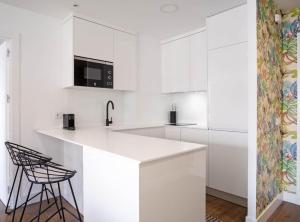 a white kitchen with a counter and stools at Principe de Vergara I in Madrid