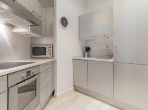 eine weiße Küche mit weißen Schränken und einer Mikrowelle in der Unterkunft San Mateo I in Madrid