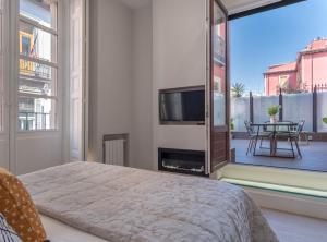 1 dormitorio con 1 cama, TV y balcón en ESPOZ Y MINA II en Madrid